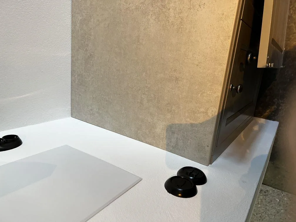 Köksbänkskiva i Dekton Lunar, matt ljust gråvit keramik, med uppvikt stänkpanel i samma sten och underlimmad diskho i ett kök i Tygelsjö.
