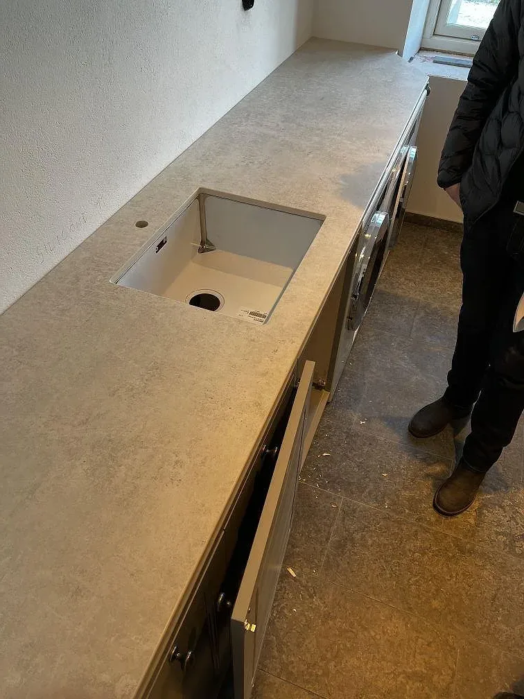 Köksbänkskiva i matt grå-vit Dekton Lunar med underlimmad diskho, mitt under montering