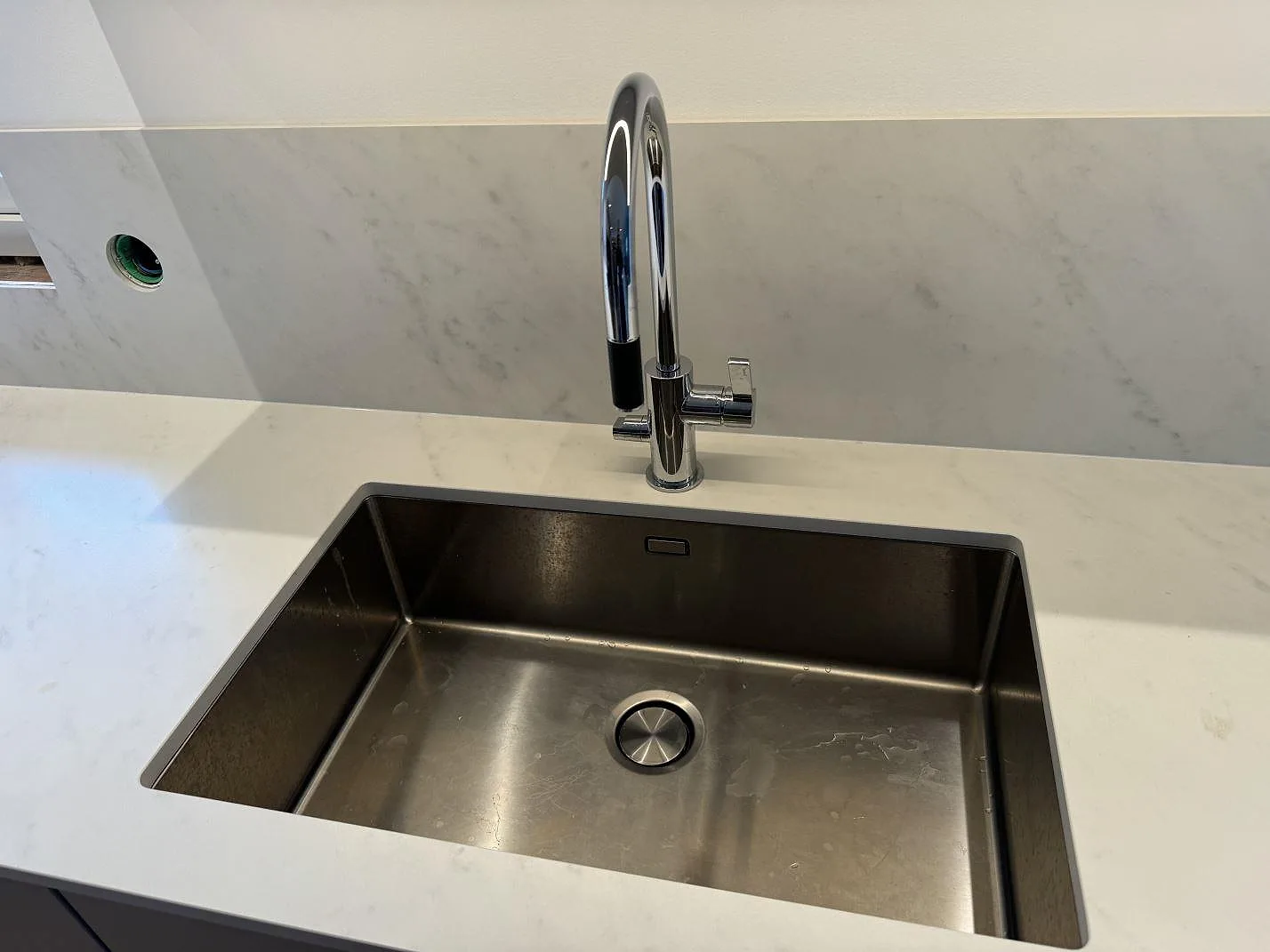 Närbild på matt Dekton Marina Kc Velvet som köksbänkskiva med diskho, blandare och låg stänkpanel i Jonstorp.