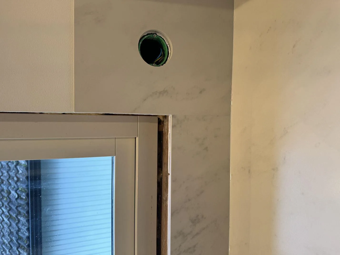 Väggpanel i matt Dekton Marina Kc Velvet runt fönster med håltagning för eluttag i köket i Jonstorp.