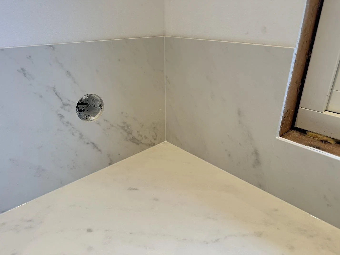Hörndetalj med bänkskiva, väggpanel och fönsternisch i matt Dekton Marina Kc Velvet i Jonstorp.