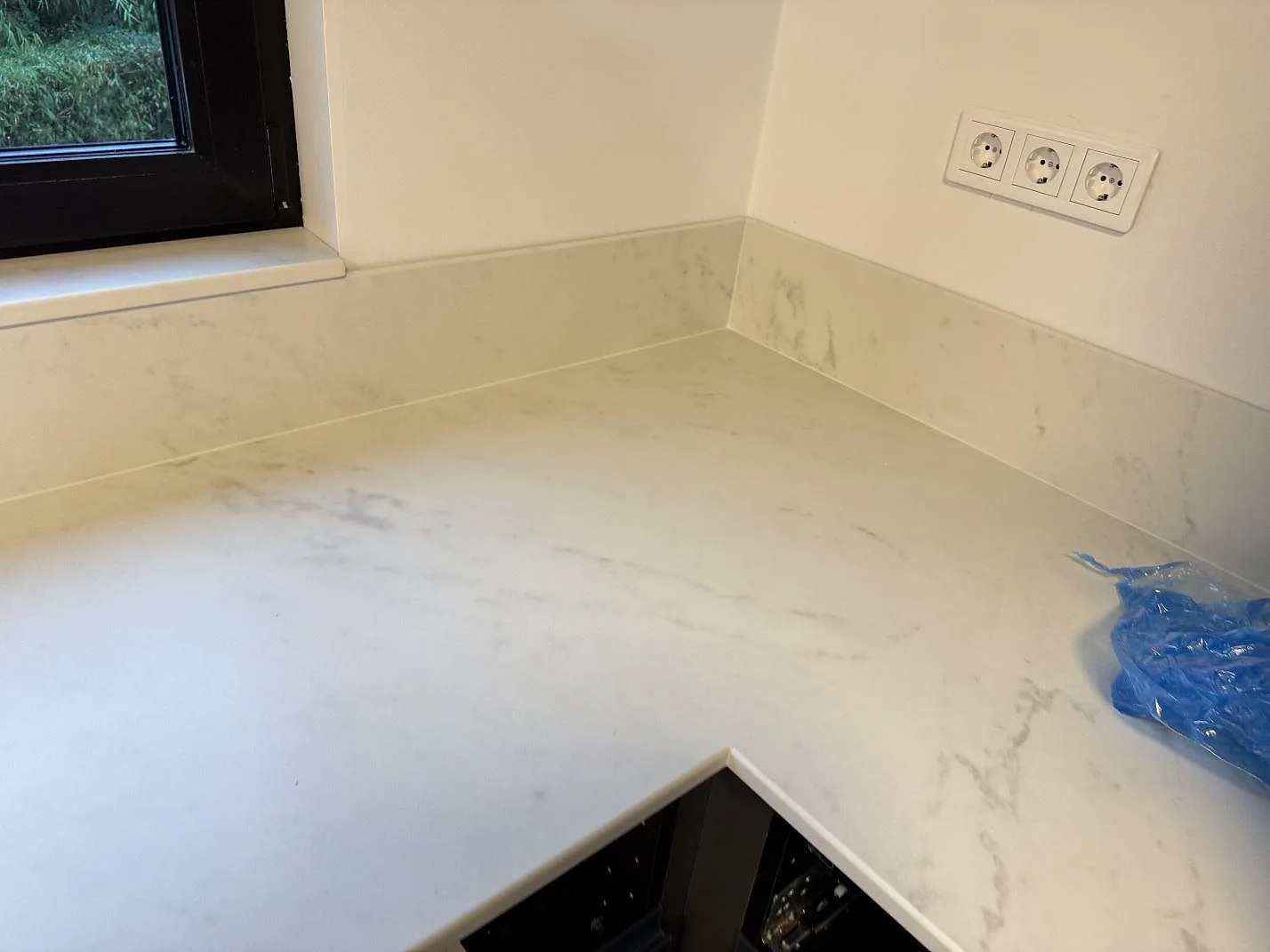 Närbild av matt Dekton Marina Kc Velvet på köksbänk med låg stänkkant, grå ådring och blå monteringsplast i Lund.