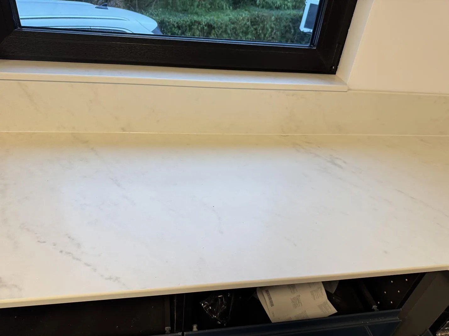 Rak del av köksbänkskiva i matt Dekton Marina Kc Velvet med stänkskydd och svart fönsterkarm i Lund.