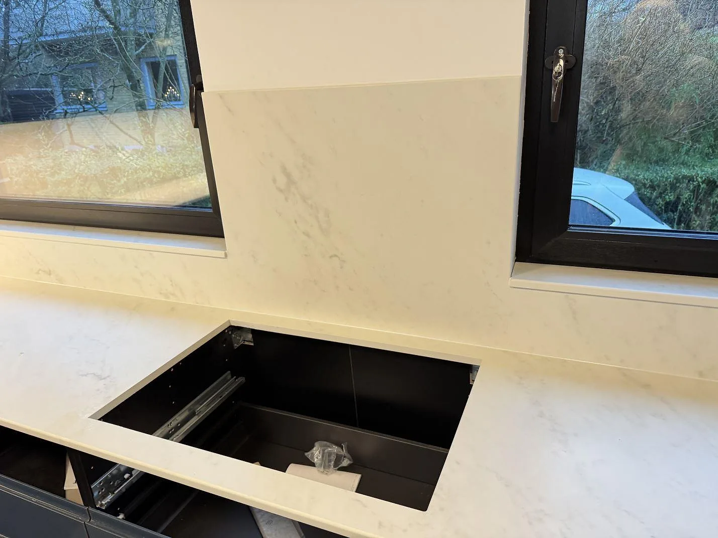 Köksbänkskiva i Dekton Marina Kc Velvet med rektangulärt urtag och högre stänkskydd mellan två fönster i Lund.