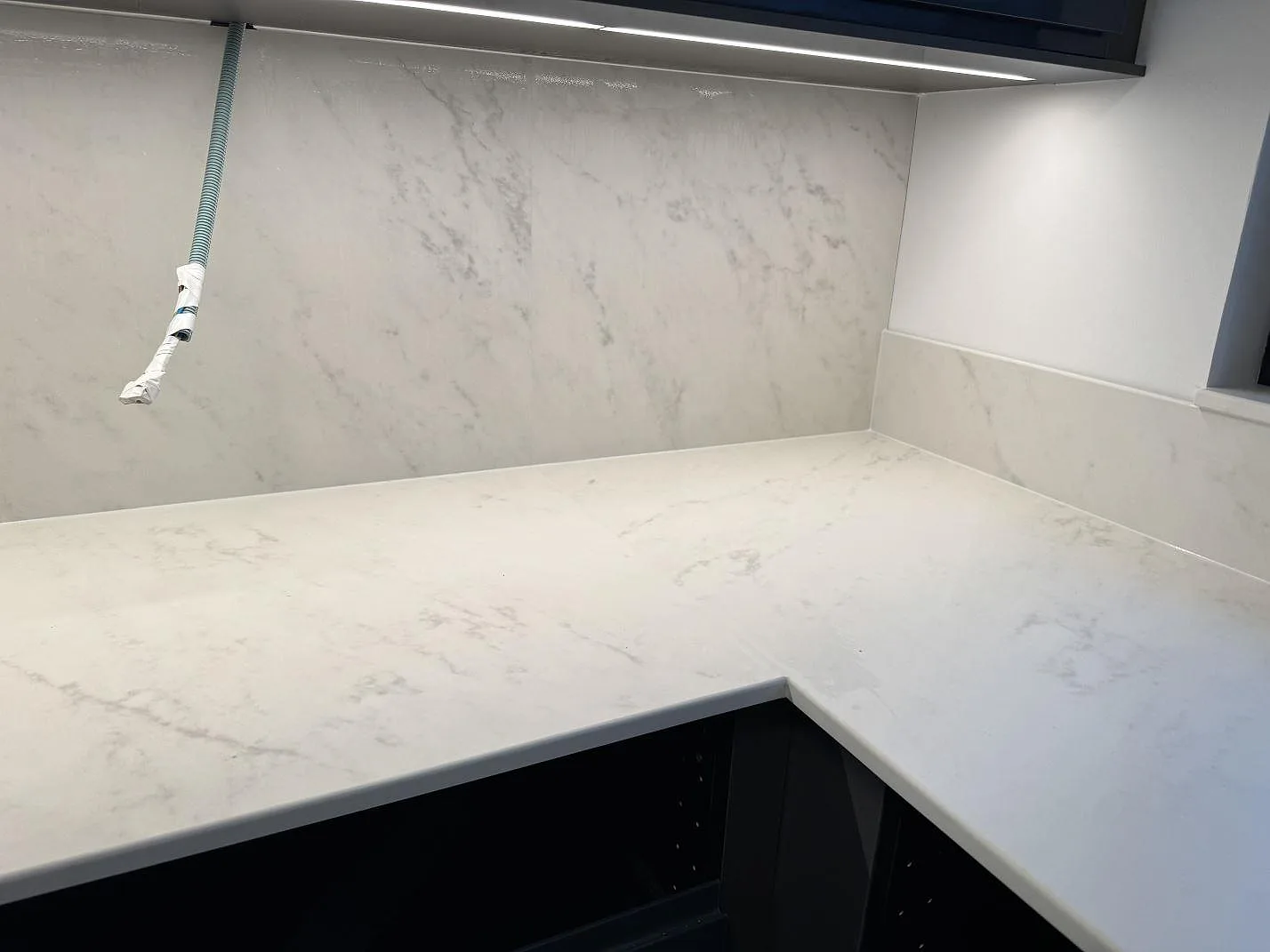 Köksbänkskiva i matt Dekton Marina Kc Velvet med högre stänkskydd och framdragen installationsslang under överskåp i Lund.