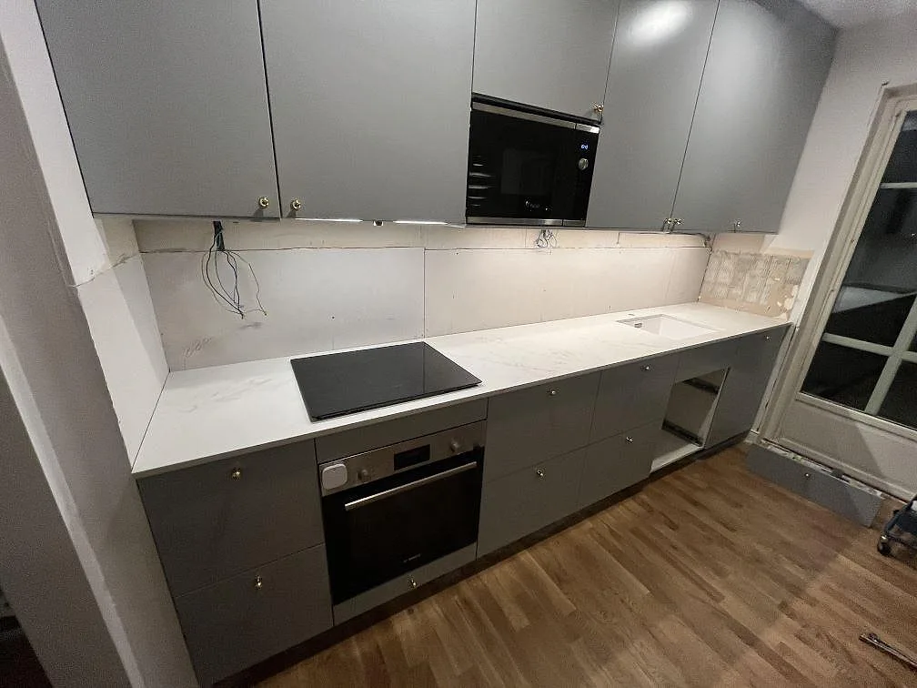 Köksbänkskiva i matt Dekton Marina Kc Velvet, 20 mm keramik, med svart häll och diskhozon i ett grått kök i Täby.