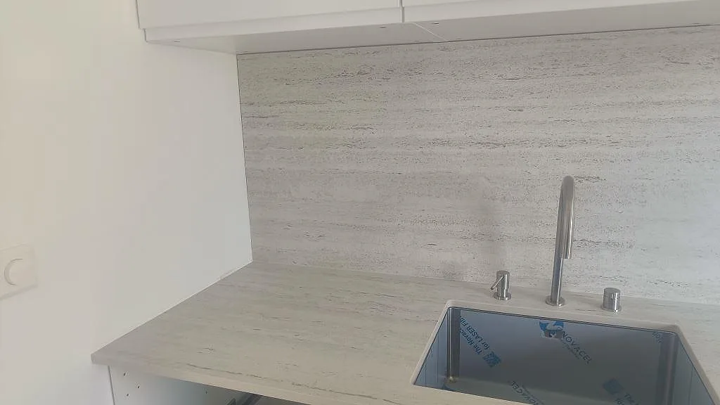 Närbild på matt Dekton Marmorio köksbänkskiva och stänkskydd med mörk diskho och blandare i Halmstad.