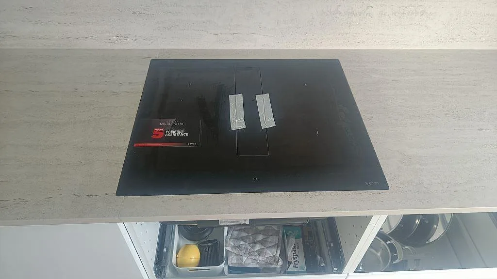 Svart häll monterad i en matt köksbänkskiva av Dekton Marmorio med ljus stenyta i Halmstad.