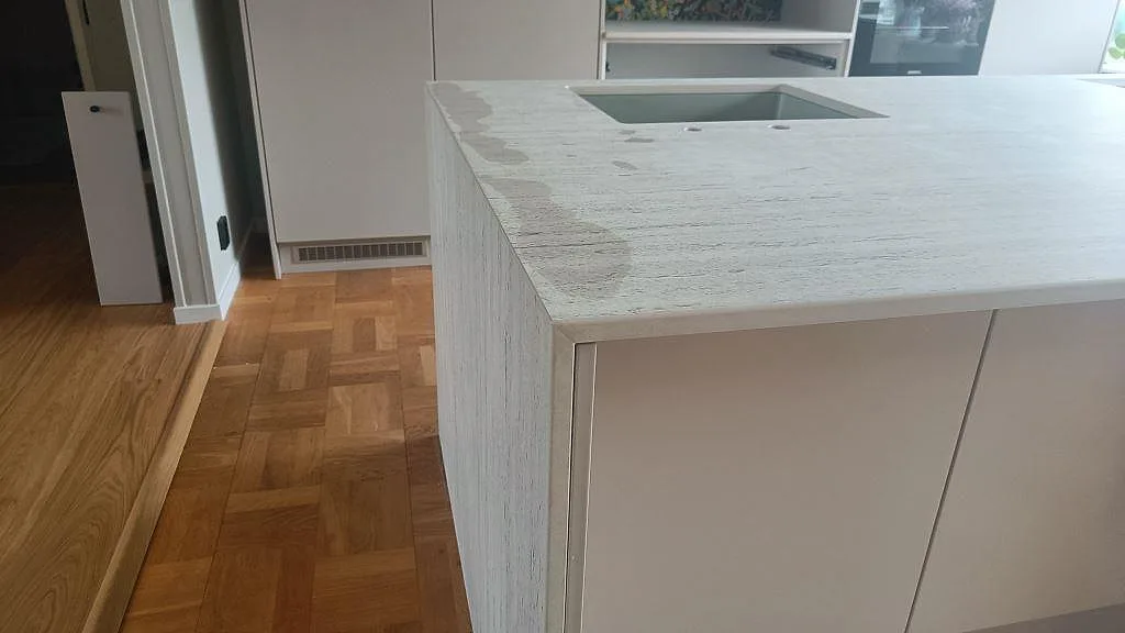 Sidovy av installerad köksö i matt Dekton Marmorio i Limhamn, med tjock kant och diskhoöppning i stenen.