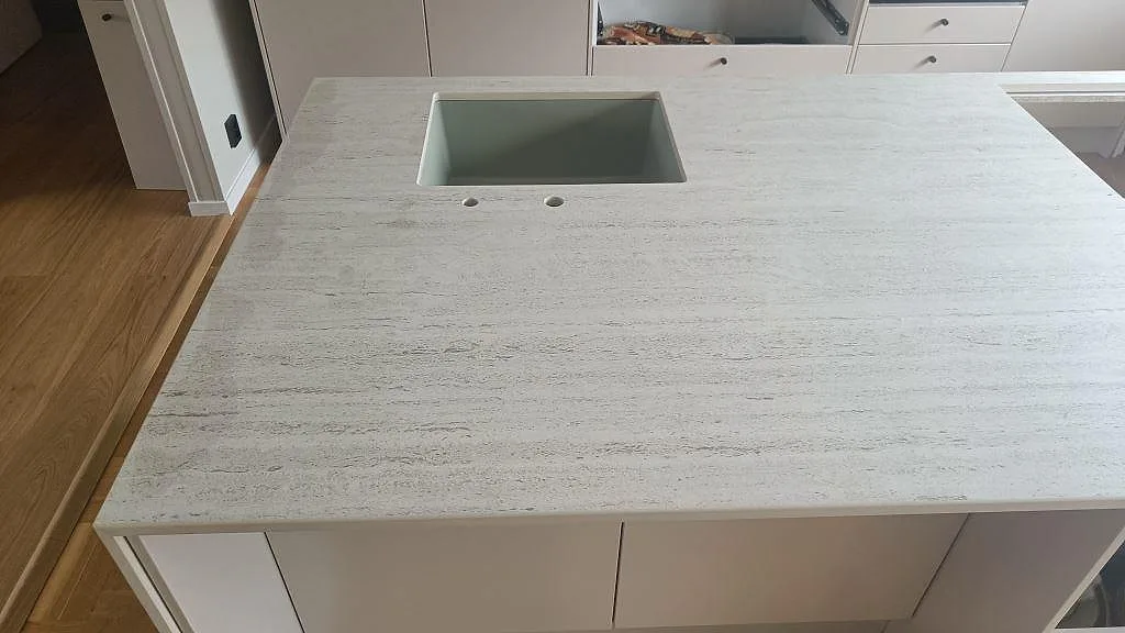 Diskhosidan av köksön i matt Dekton Marmorio i Limhamn, med underlimmad ho och synlig vitgrå ådring.