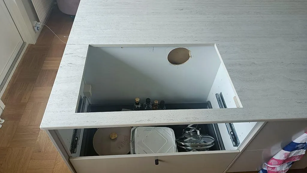 Hällöppning i en matt Dekton Marmorio bänkskiva på köksö i Limhamn, med öppen köksstomme under stenen.