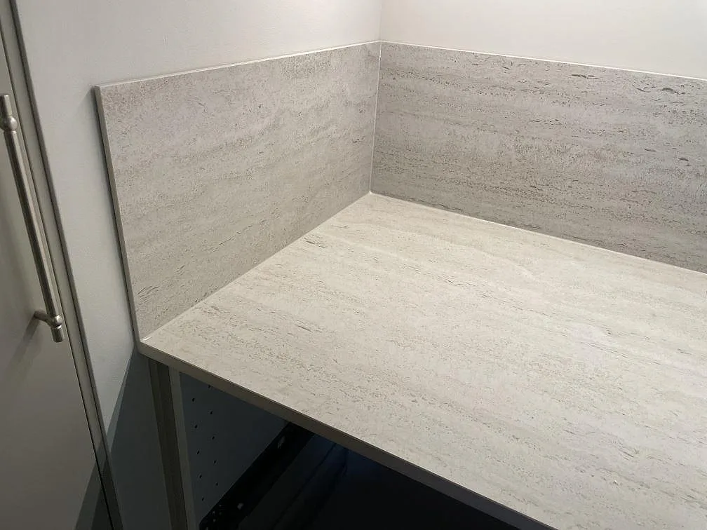 Hörndetalj med köksbänkskiva och stänkskydd i matt Dekton Marmorio över vita stommar i Malmö.