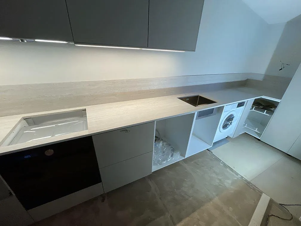 L-formad köksbänkskiva i matt Dekton Marmorio med underlimmad rostfri diskho, stänkskydd och integrerad vitvara i Malmö.