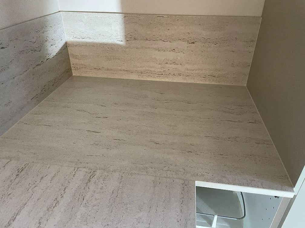 Arbetsyta i matt Dekton Marmorio med uppvikt stänkskydd och ljus stenstruktur i ett kök i Malmö.