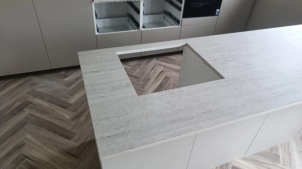 Närbild på hällöppning i matt Dekton Marmorio på en köksö med öppna stommar under montering i Mölndal.
