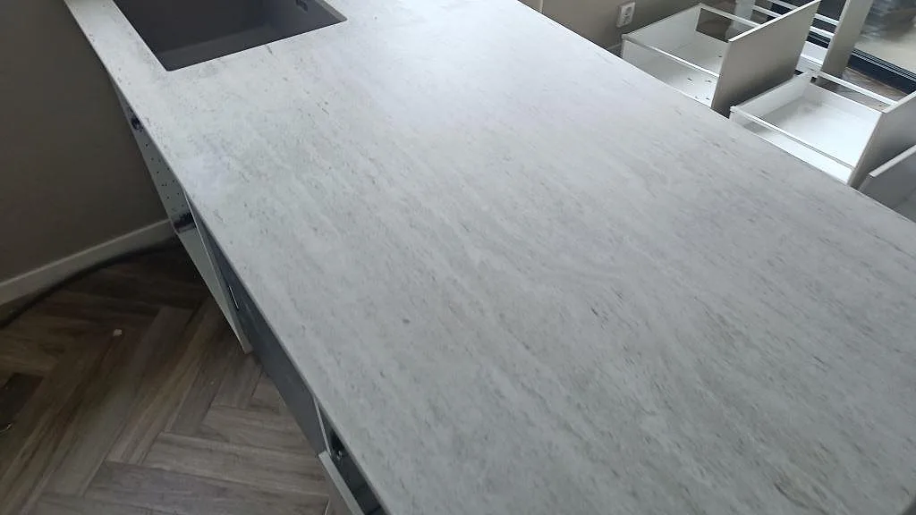Ytnära bild av den matta Dekton Marmorio skivan med ljus grå ådring på köksö i Mölndal.