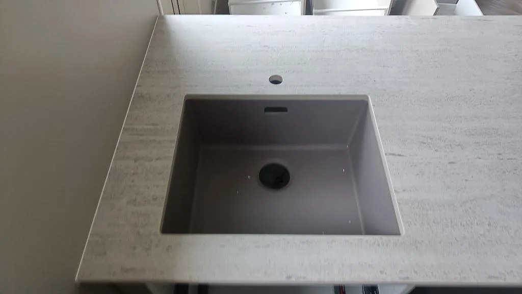 Detalj av diskho i en ljus köksbänkskiva i matt Dekton Marmorio keramik i Mölndal.