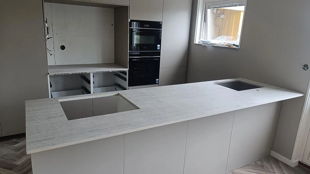 Köksbänkskiva i 20 mm matt Dekton Marmorio keramik med hällöppning och diskho på köksö i Mölndal.