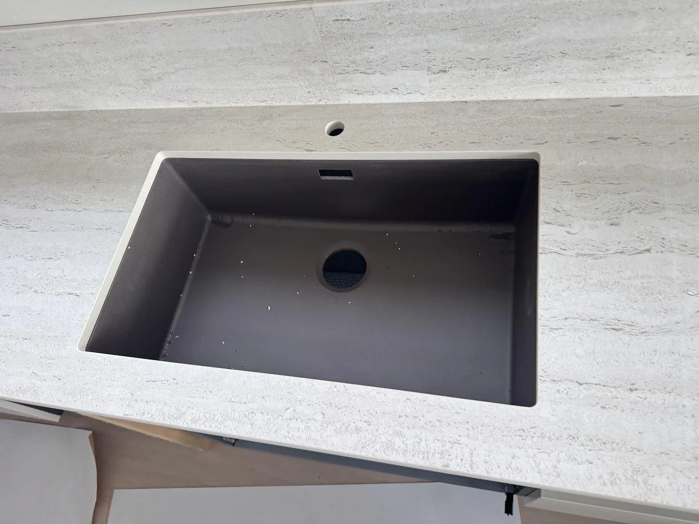 Närbild av mörk diskho i matt Dekton Marmorio keramik med linjär ådring och förborrat blandarhål i Skurup.