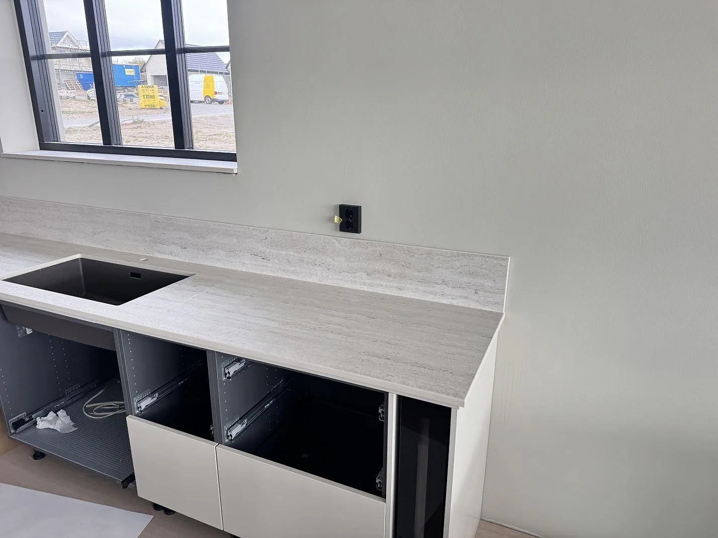 Väggbänk i matt Dekton Marmorio keramik med mörk diskho och låg stänkkant under fönster i Skurup.
