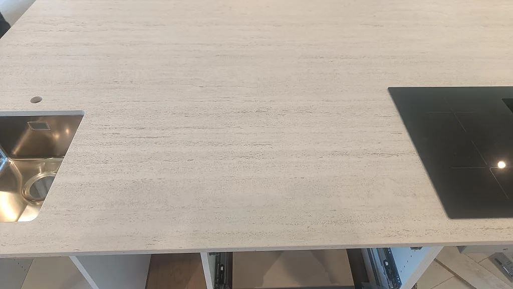 Detalj av matt Dekton Marmorio bänkskiva mellan rostfri diskho och svart induktionshäll i ett kök i Uddevalla.