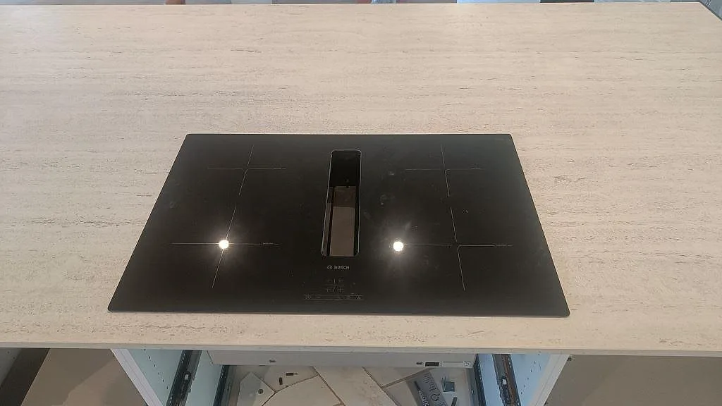 Svart induktionshäll infälld i en ljus matt Dekton Marmorio köksbänkskiva på köksön i Uddevalla.
