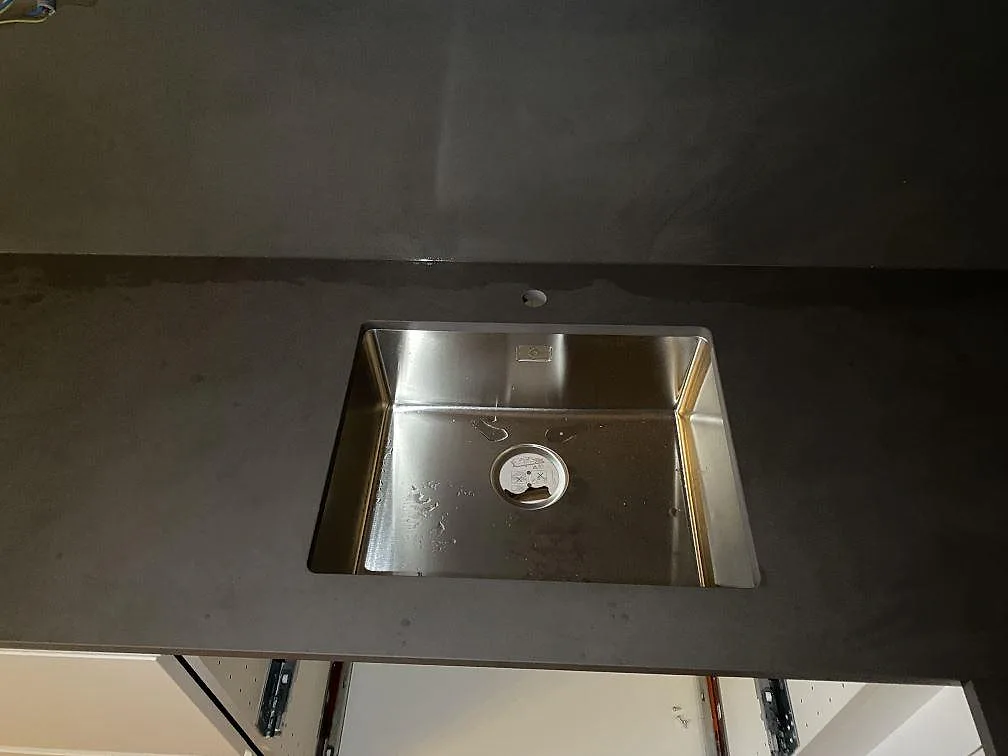 Detalj av mörk Dekton Micron bänkskiva med monterad diskho i ett kök under montering i Bunkeflostrand.