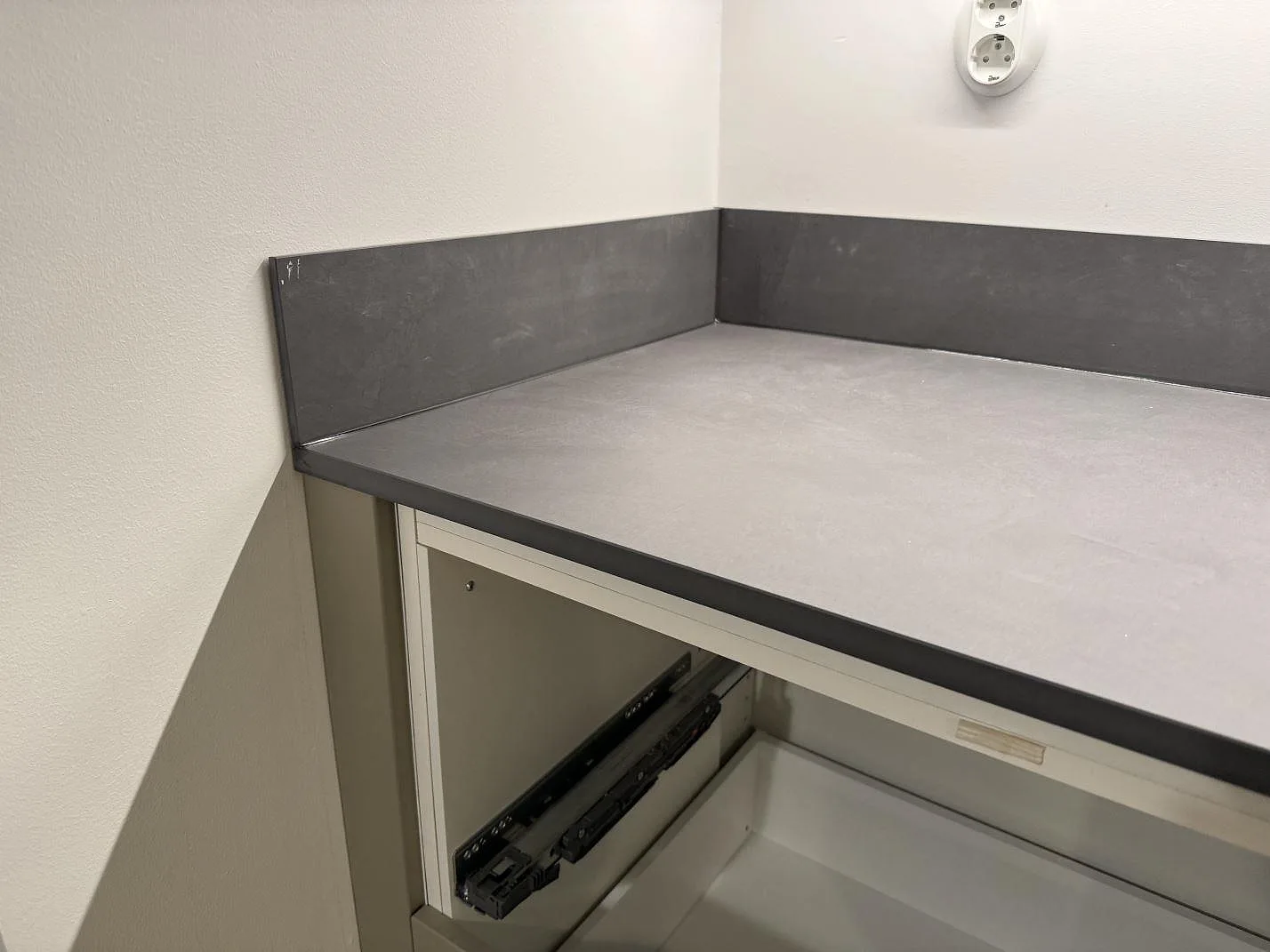 Detalj av matt Dekton Micron keramik med uppvikt stänkkant i hörn på bänkskiva i Olofström.