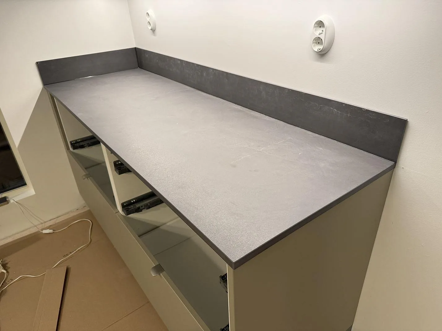 Grå matt Dekton Micron bänkskiva med låg stänkkant och öppna köksstommar i Olofström.