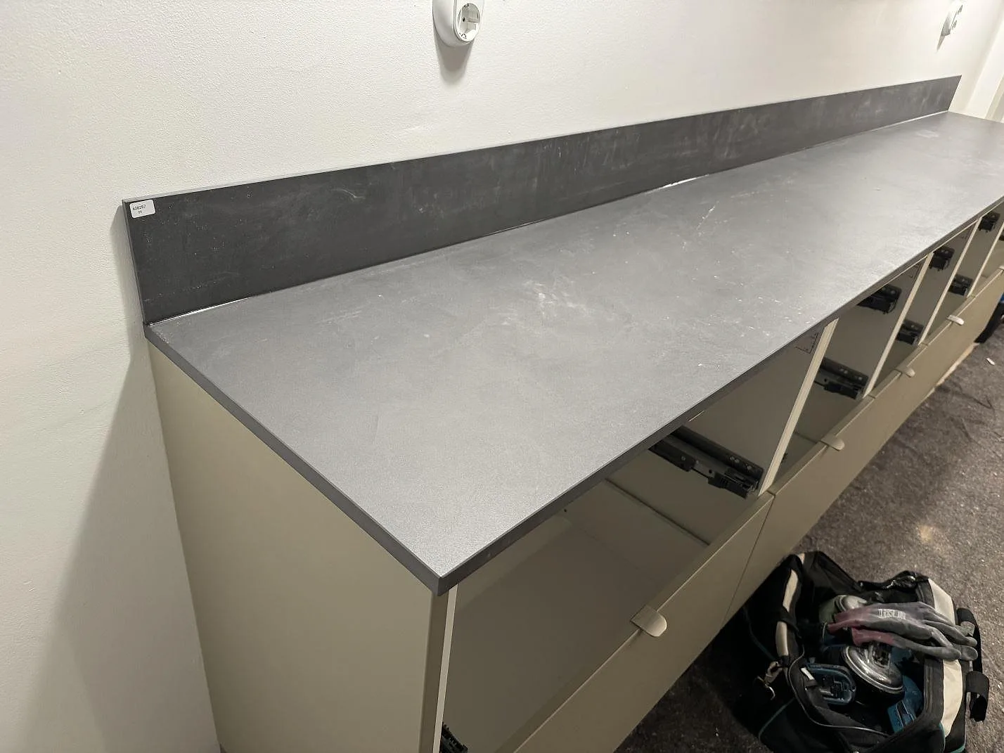 Matt köksbänkskiva i grå Dekton Micron keramik med uppvikt stänkkant på öppna stommar i Olofström.