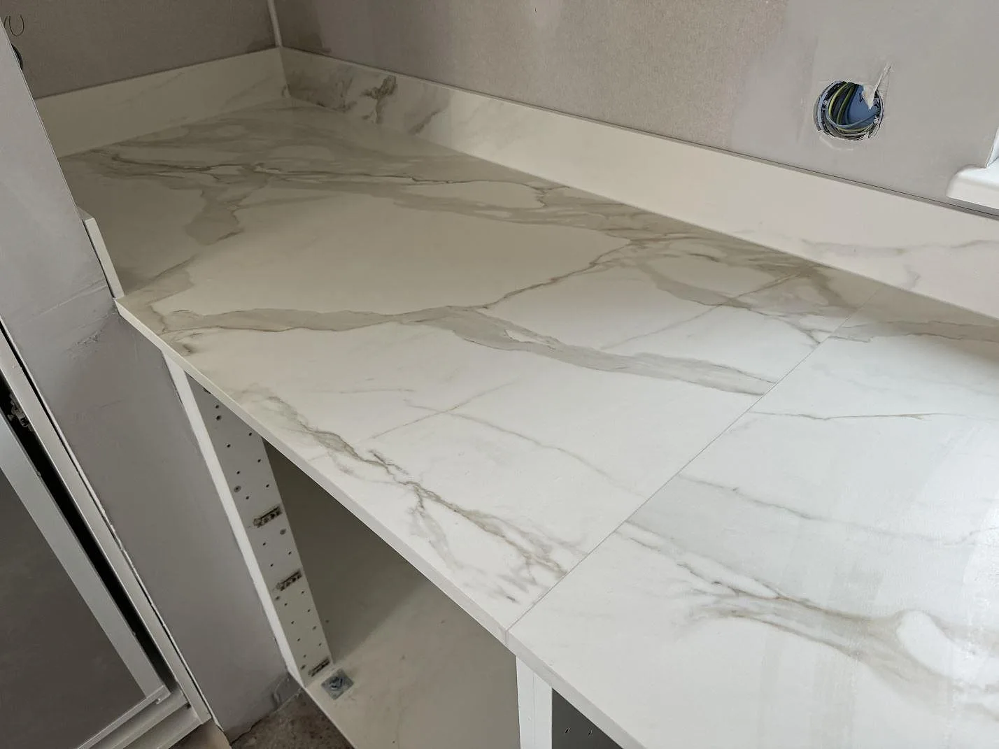 Installerad köksbänkskiva i matt Dekton Morpheus Velvet med låg stänkkant och synliga öppna skåpstommar i Billesholm.