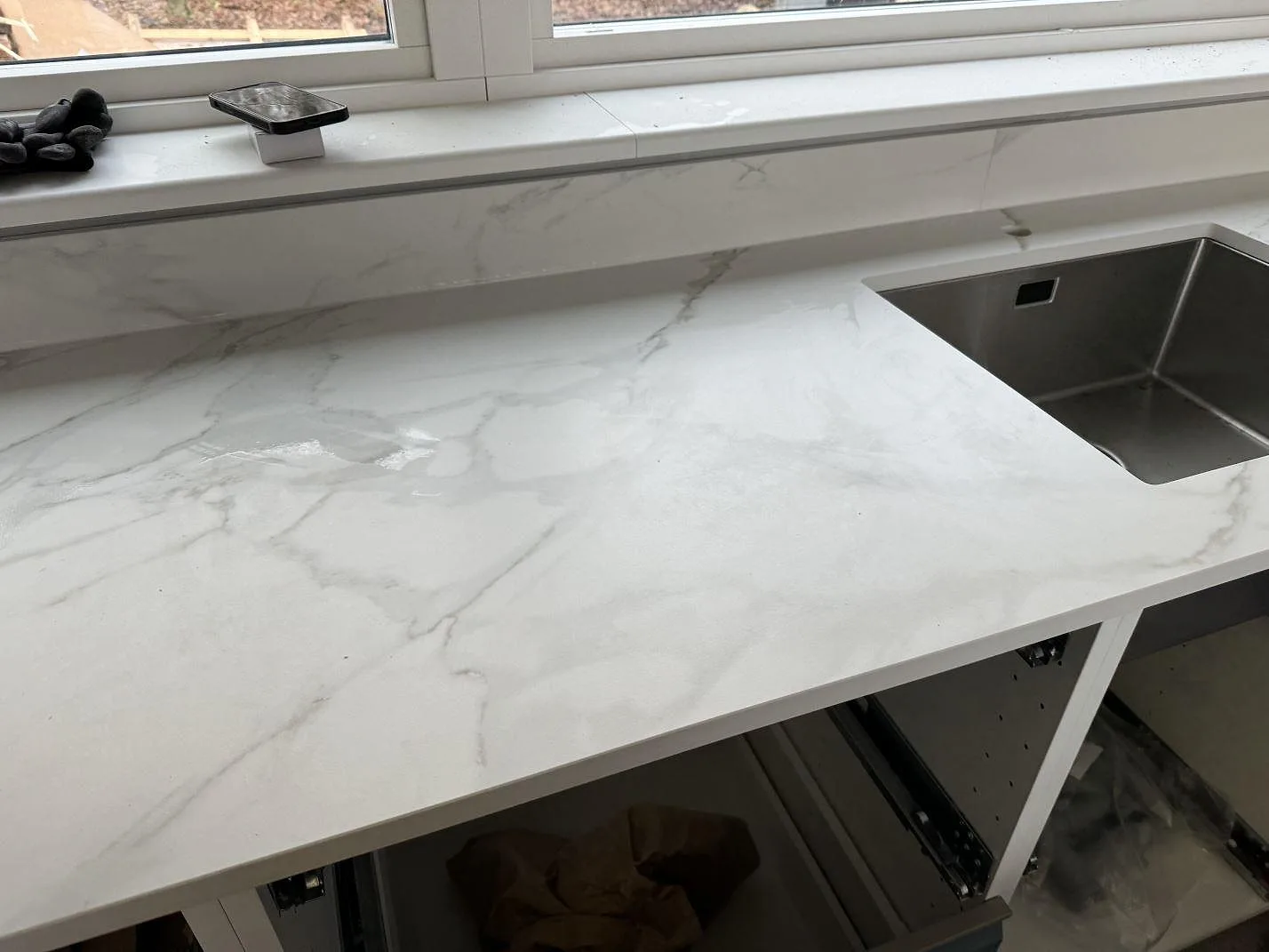 Diskbänksdel i matt Dekton Morpheus Velvet med underlimmad rostfri diskho och låg stänkkant under fönster i Billesholm.