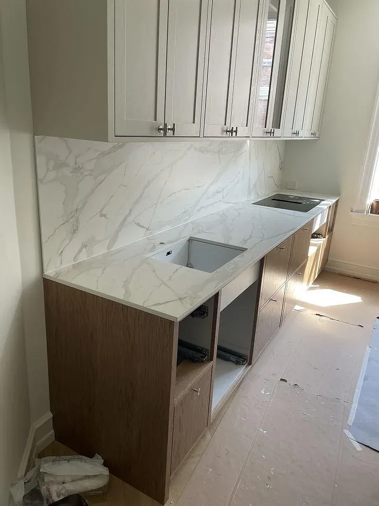 Köksbänkskiva i Dekton Morpheus Velvet sett över köket i Frederiksberg under montering, matt keramik med induktionshäll och ljusa och mörka stommar.