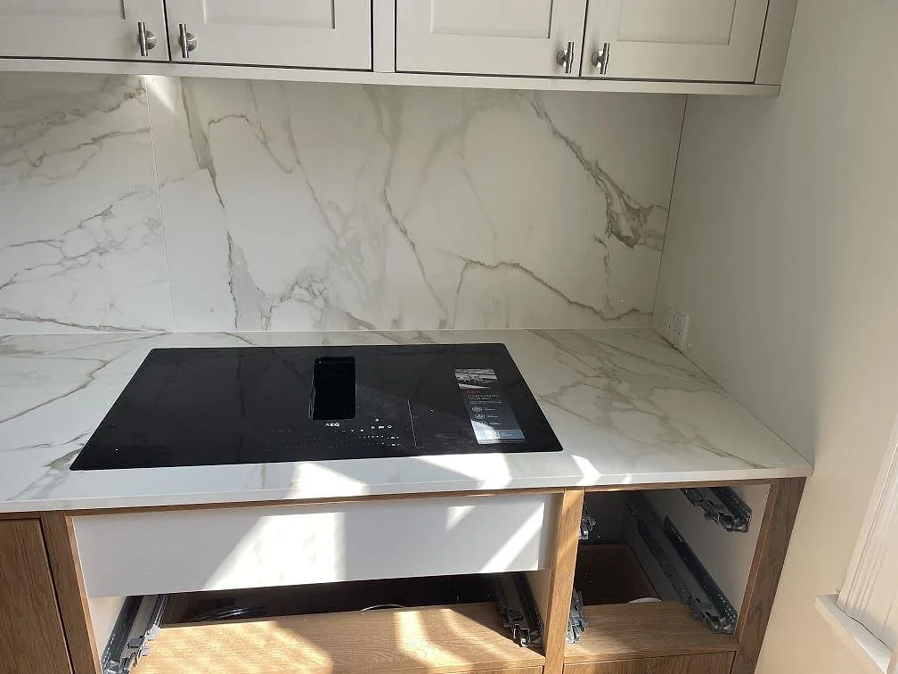 Matt Dekton Morpheus Velvet köksbänkskiva med infälld svart induktionshäll och stänkskydd i samma keramik i ett kök i Frederiksberg.