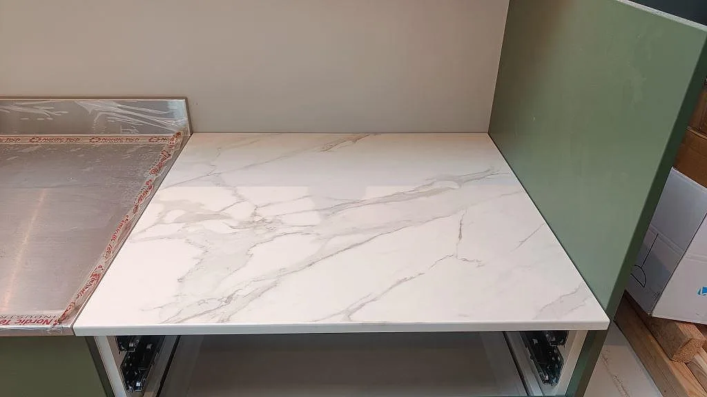 Kort bänkdel i vit Dekton Morpheus Velvet keramik med matt yta och grå ådring i ett kök i Kungsbacka.