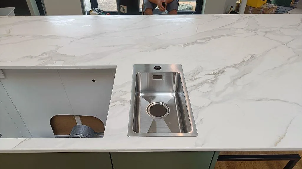 Närbild på matt Dekton Morpheus Velvet med rostfri diskho och större utskärning i köksön i Kungsbacka.