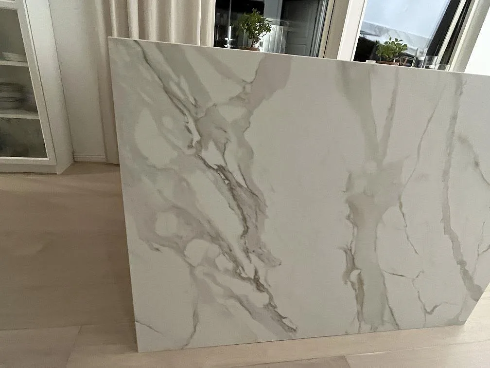 Sidovy av köksö i keramisk Dekton Morpheus Velvet, matt, med stora grå ådringar i Södertälje.