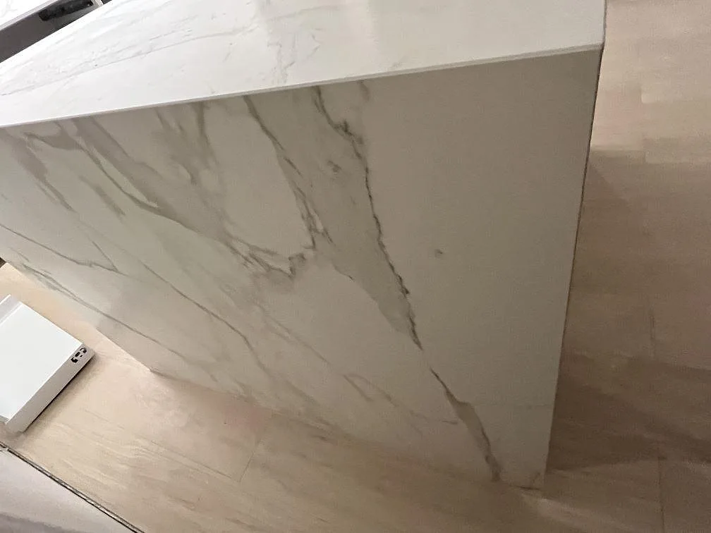 Närbild på sidobeklädnad i matt keramisk Dekton Morpheus Velvet med marmorerad ådring på köksö i Södertälje.