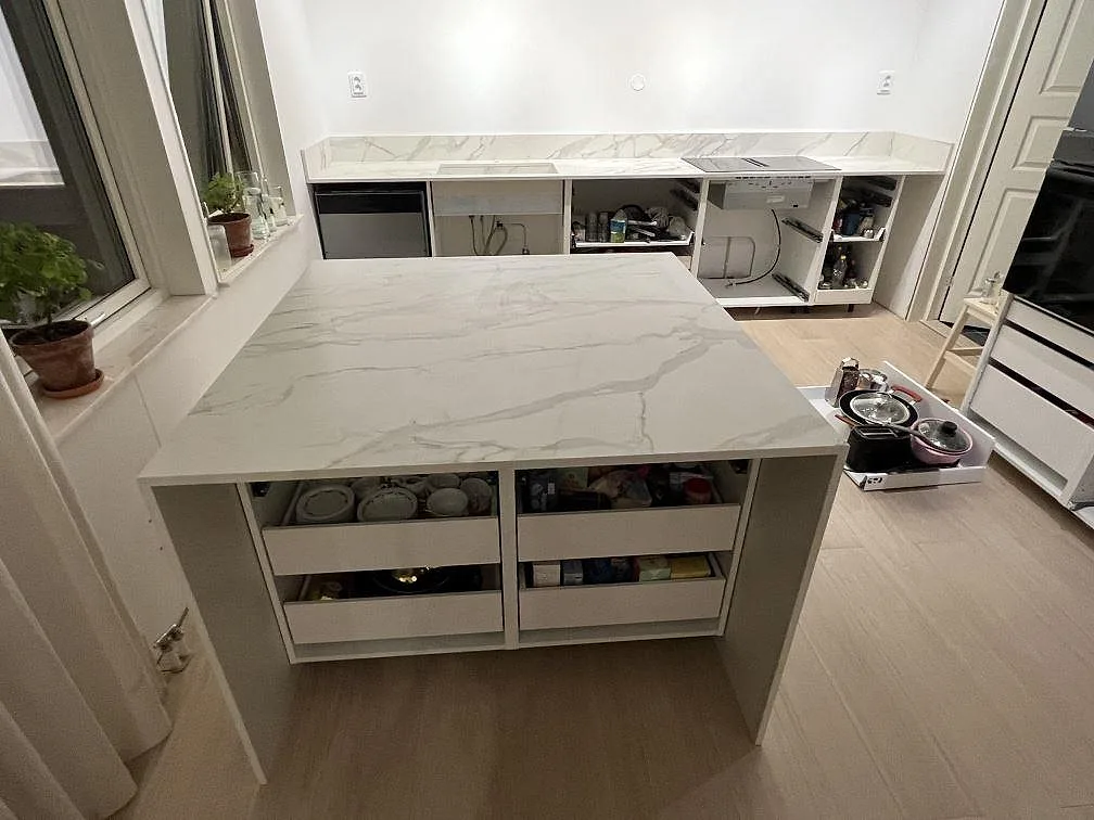 Köksö i keramisk Dekton Morpheus Velvet, matt, med vit marmorerad ådring i ett kök under montering i Södertälje.