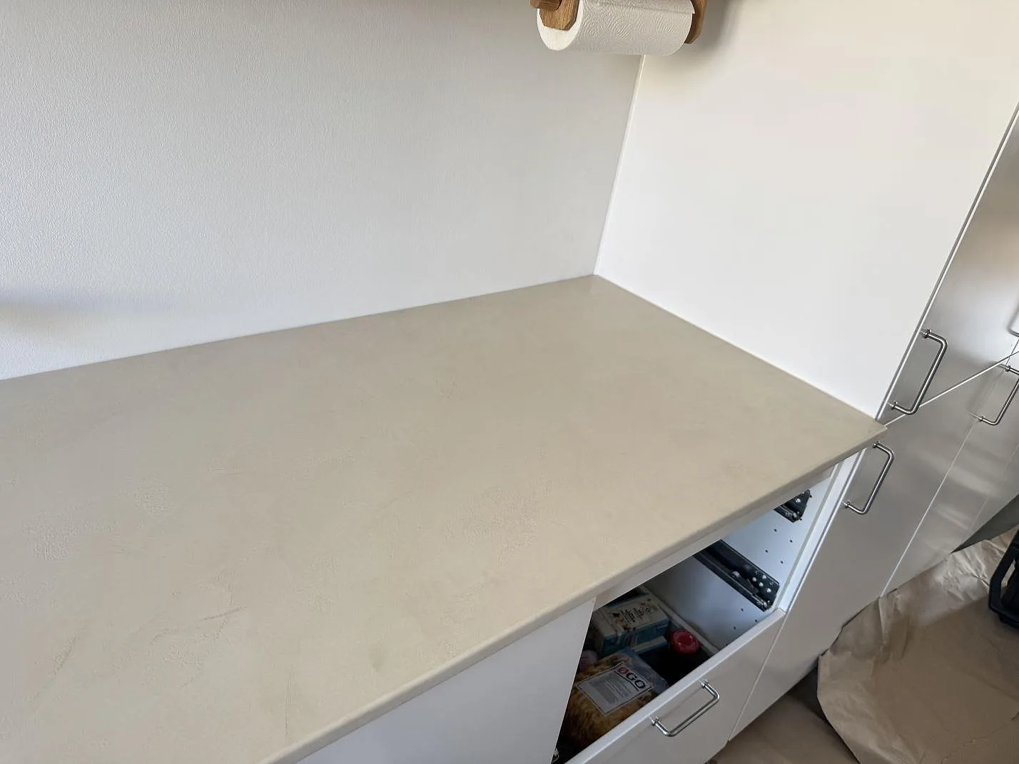 Monterad köksbänkskiva i matt Dekton Nacre Velvet med öppen skåpstomme och vägganslutning i Frederiksberg.