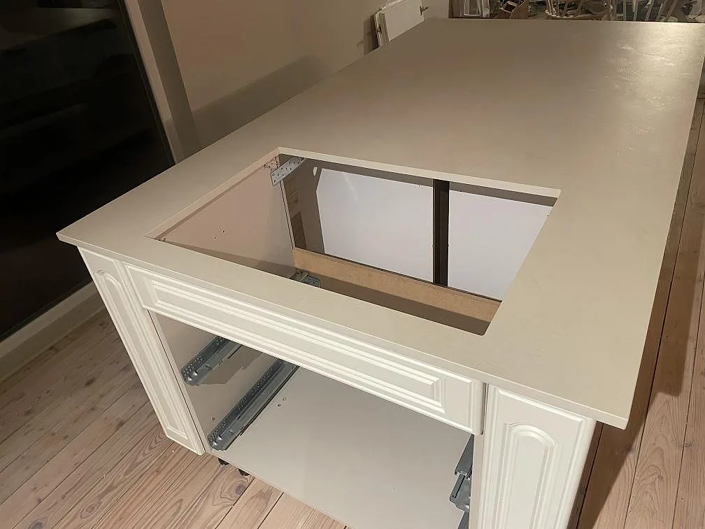 Närbild på rektangulärt urtag i matt Dekton Nacre Velvet på köksö med profilerade vita stommar i Immeln.