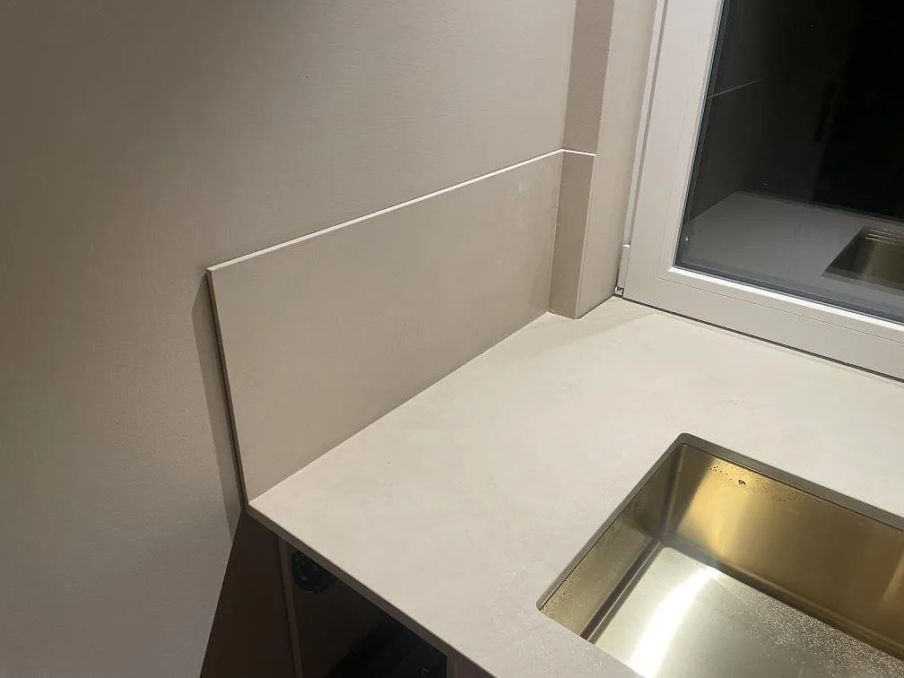 Bänkskiva i matt Dekton Nacre Velvet med låg stänkkant och rostfri diskho vid fönster i köket i Immeln.