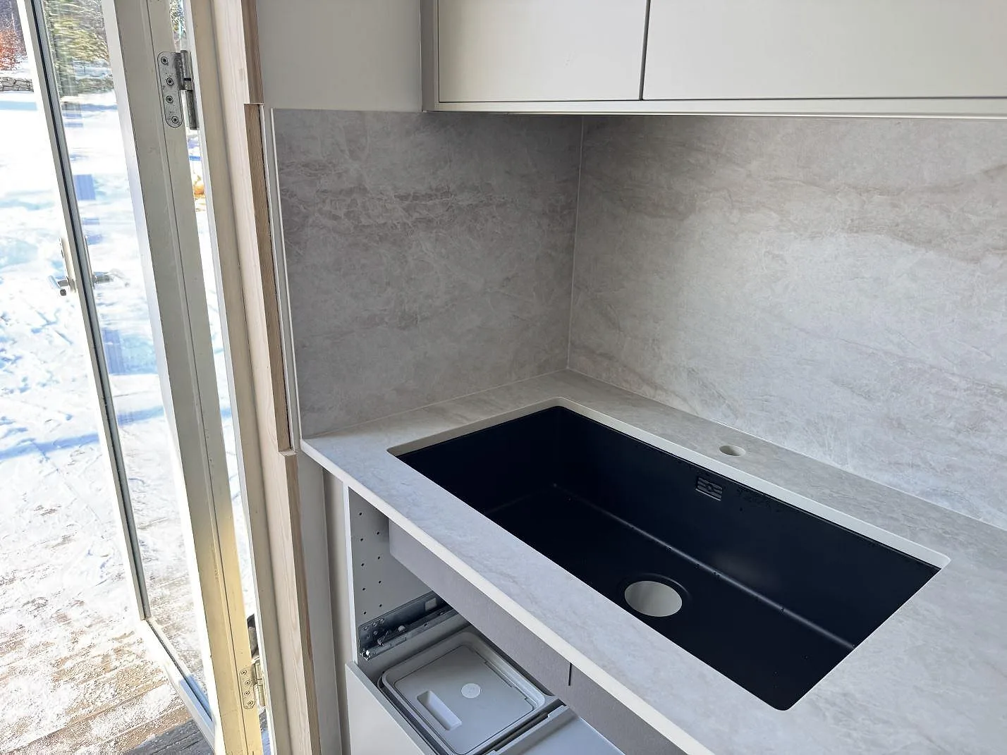 Svart underlimmad kompositdiskho i en matt Dekton Nara köksbänkskiva med lågt stänkskydd i ett kök i Fjärås.