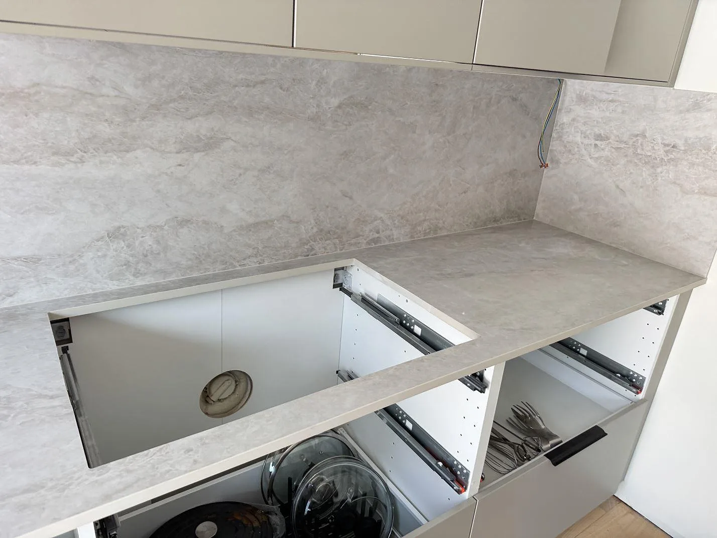 Vinklad köksbänkskiva i matt Dekton Nara med heltäckande stänkskydd i samma sten över överskåp i ett kök i Fjärås.