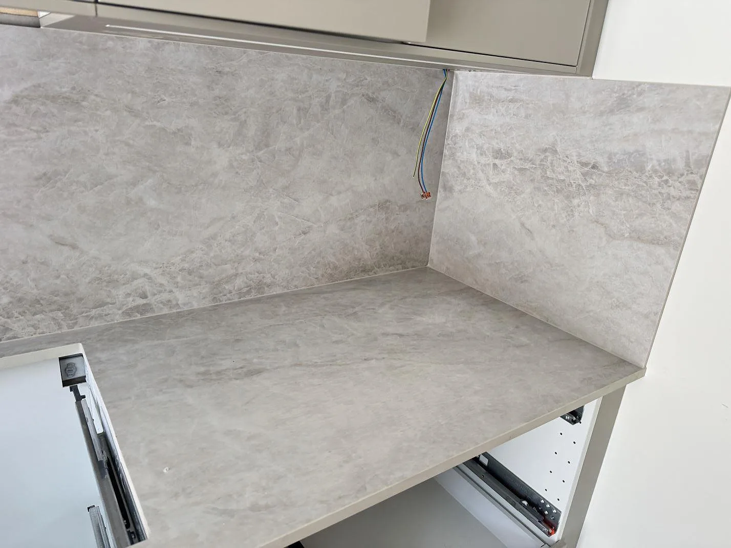 Hörnparti av en matt Dekton Nara köksbänkskiva med stänkskydd i greige keramik i ett kök i Fjärås.