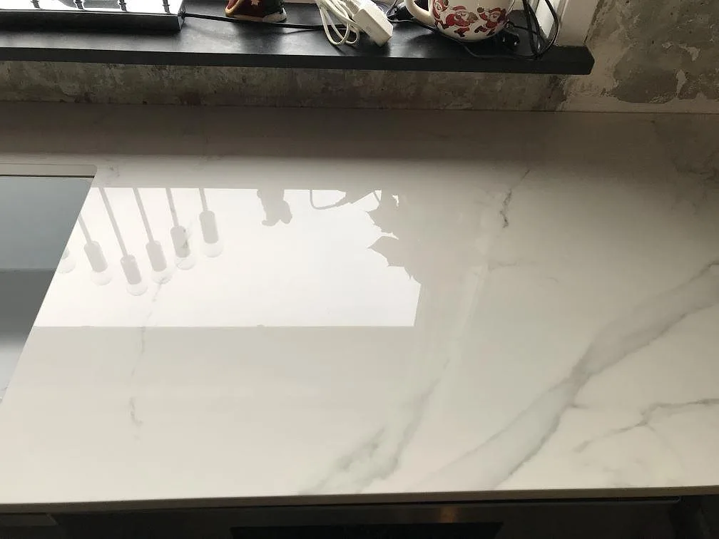 Polerad Dekton Natura köksbänkskiva med spegelblank yta och mjuk grå ådring i ett kök i Bara.