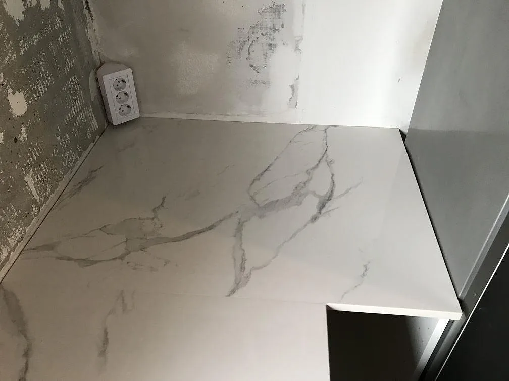 Vit Dekton Natura bänkskiva i hörnläge mot vägg under montering i ett kök i Bara.
