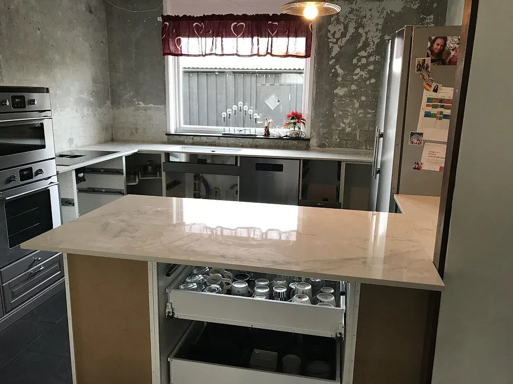 Köksbänkskiva i vit Dekton Natura, polerad keramik med marmorlik ådring, monterad i ett U format kök i Bara.
