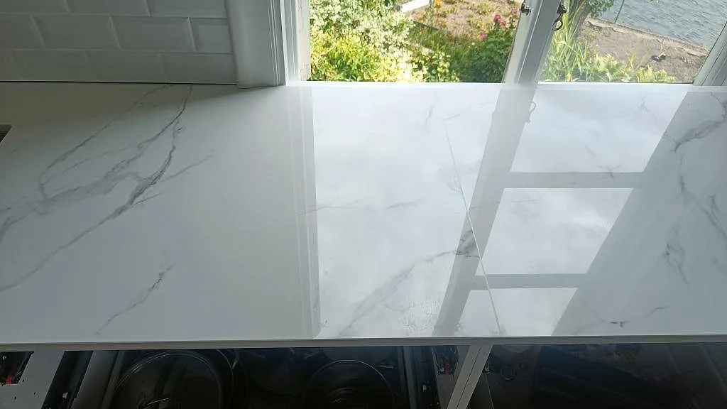 Vit Dekton Natura köksbänkskiva med infälld induktionshäll och fönster i ett kök i Karlskrona.