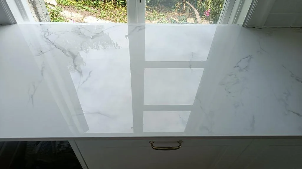 Polerad Dekton Natura bänkskiva i keramik med grå ådring och mässingshandtag i ett kök i Karlskrona.
